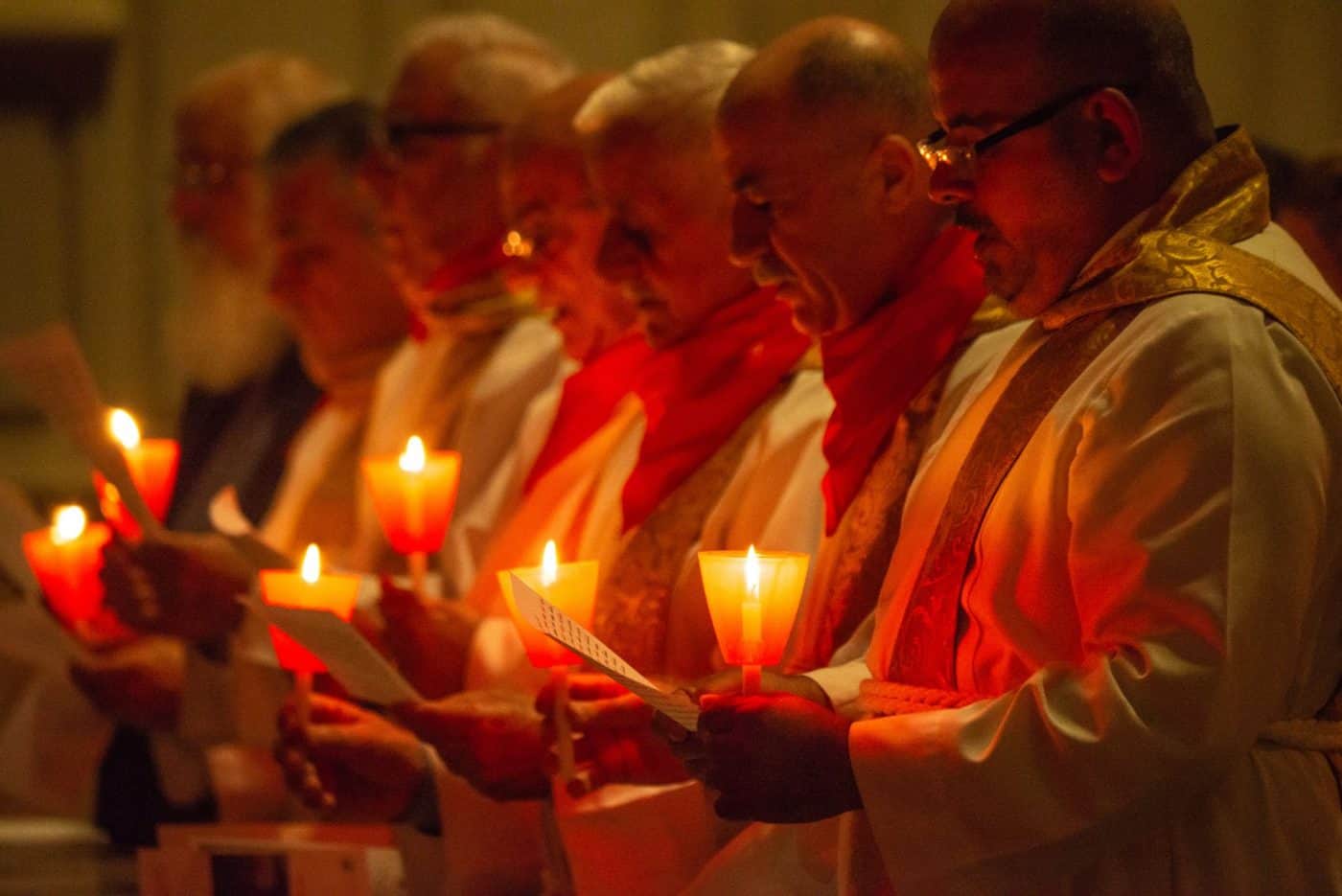 Priests holding red candles in prayer for persecuted Christians during Red Week